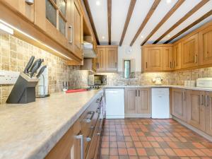 a large kitchen with wooden cabinets and a tile floor at Rhandir Barn in Ffair-fâch