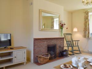 a living room with a fireplace and a mirror at Dulcie Cottage in Benson