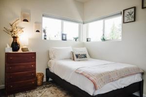 a bedroom with a bed and a dresser and two windows at The Berkeley House in Klamath Falls