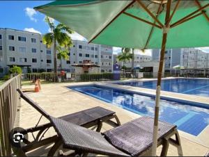 a chair with an umbrella next to a swimming pool at Apto Familiar in Aracaju