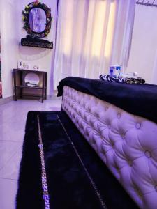 Una habitación con una cama con una manta negra y un espejo. en Chambre Meublé avec Toillette intérieure chauffe eau Wi-Fi Smart Tv, en Dakar