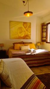 a bedroom with two beds and a painting on the wall at Posada El Prado in Salta