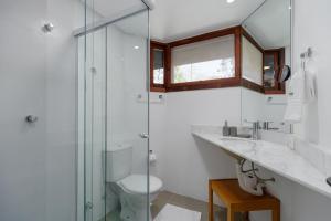 a bathroom with a toilet and a glass shower at Casa Sonnendorf 4 dorm Centro by Achei Gramado in Gramado
