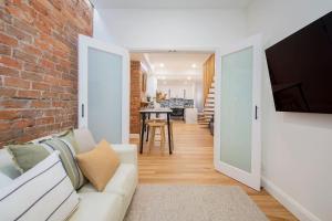a living room with a white couch and a brick wall at Casa Dianna - Timeless Terrace near CBD and Waterfront in Newcastle