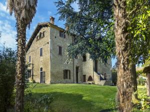 una vecchia casa in pietra con alberi in primo piano di Large apartment in a farmhouse a Modigliana
