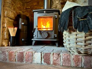 estufa de leña en una chimenea de ladrillo en Snowdrop Cottage, en Bulmer