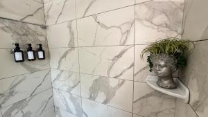 法洛克威Serenity Room JFK的浴室设有大理石墙壁和植物花瓶