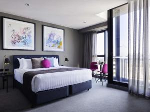 une chambre avec un grand lit avec des oreillers roses dans l'établissement Art Series - The Chen, à Box Hill