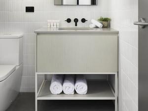 une salle de bain avec un lavabo et une étagère avec des serviettes dans l'établissement Art Series - The Chen, à Box Hill