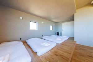 een kamer met vier witte bedden bij Yunagi 夕凪 