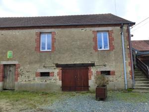 una vecchia casa di mattoni con una porta di legno e una scala di Charmant gîte nature 2 chambres, rando GRP, près de Montluçon, cour commune - FR-1-489-418 a Saint-Palais