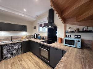 a kitchen with a stove and a microwave at Gîte cosy avec spa, jeux extérieurs et animaux acceptés - FR-1-489-467 in Saint-Léon