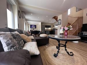 a living room with a couch and a table at Gîte cosy avec spa, jeux extérieurs et animaux acceptés - FR-1-489-467 in Saint-Léon