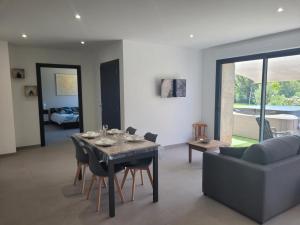 a living room with a table and a couch at Gîte rénové avec piscine couverte chauffée, spa, climatisation et équipements PMR à Couzon - FR-1-489-483 in Couzon
