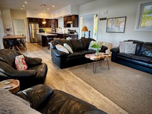 ein Wohnzimmer mit Ledersofas und einem Tisch in der Unterkunft Whitecaps Retreat Beach House 