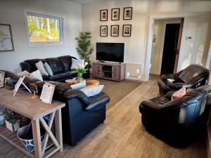 ein Wohnzimmer mit Ledersofas und einem TV in der Unterkunft Whitecaps Retreat Beach House 
