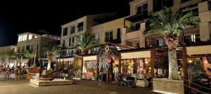 a city street with palm trees and buildings at night at Blue Bay Boutique Studio in Đenovići