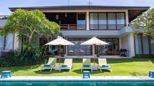 a group of chairs and umbrellas in front of a house at Villa Aiko in Jimbaran