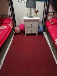 une chambre avec deux lits et un tapis rouge dans l'établissement ABD Cottages, à Abu Dhabi