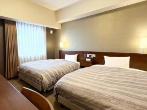 Postel nebo postele na pokoji v ubytování Hotel Route-Inn Utsunomiya Miyukicho -Kokudou4gou-