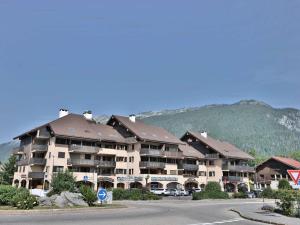 a large apartment building with a mountain in the background at Charmant studio avec cabine - 4 pers - St Jean de Sixt - FR-1-458-223 in Saint-Jean-de-Sixt