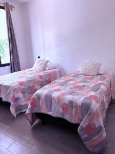 a bedroom with two beds and a window at Casa Guaria Morada in Valle de Bravo