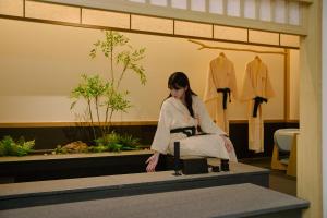 a woman is sitting on a table in a store at Aank Ryokan Hotel Songtan in Pyeongtaek