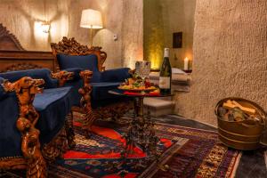ein Wohnzimmer mit einer Couch und einem Tisch mit einer Flasche Wein in der Unterkunft Signature Cave Cappadocia, Trademark Collection by Wyndham in Ürgüp