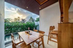 a dining room with a table and chairs and a large window at Delatari Villa in Ubud
