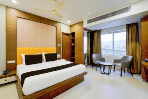 ティルパティにあるTownhouse OAK Hotel Vista Orchidのベッドとテーブルと椅子のある寝室
