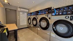 a laundry room with three washing machines in it at Port House Honmachi in Tokyo