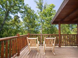 two chairs sitting on a wooden deck with trees at Cupids Arrow Holiday home in Gatlinburg