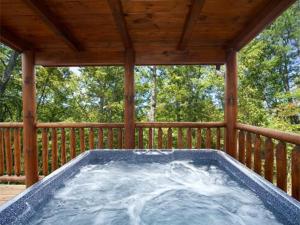 a hot tub on a porch with a wooden deck at Cupids Arrow Holiday home in Gatlinburg