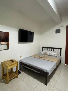 ein Schlafzimmer mit einem Bett und einem Fernseher an der Wand in der Unterkunft D and A Transient Inn Taguig in Taguig