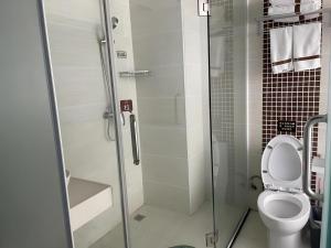 une salle de bain avec toilettes et douche en verre dans l'établissement Thank Inn Hotel Hainan Sanya Sanya Bay Seascape Branch, à Sanya