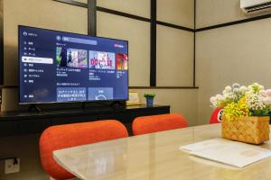 a tv sitting on top of a table with orange chairs at 新大阪旅庵 民泊彩庵 in Osaka
