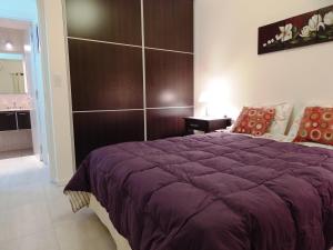 a bedroom with a purple bed with a large headboard at Departamento Villa Carlos Paz 2 Adultos in Villa Carlos Paz