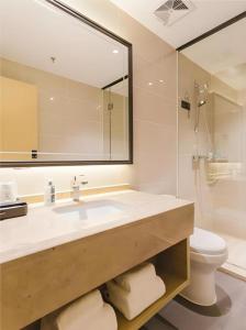 a bathroom with a sink and a toilet and a mirror at City Comfort Inn Foshan Sanshui Datang in Xingrenbi +63 photos