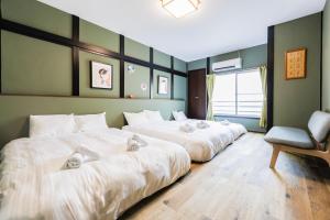 three beds in a room with a chair at 新大阪旅庵 民泊彩庵 in Osaka