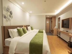 a large bedroom with a large bed and a television at GreenTree Inn Express Shandong Zaozhuang Shizhong District Huashan Road Ginza in Zaozhuang