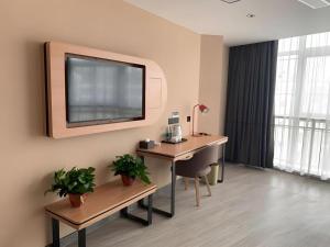 Elle comprend un bureau avec un bureau et une télévision murale. dans l'établissement Thank Inn Hotel Shandong Heze Mudan District Bayi Road Pedestrian Street, à Zhaolou
