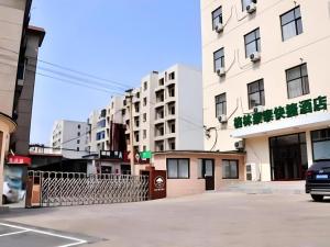 a car driving down a street next to tall buildings at GreenTree Inn Dalian Jinzhou District Railway Station Ansheng Plaza in Jinzhou