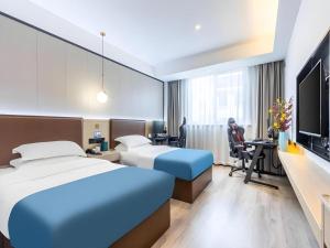 a hotel room with two beds and a flat screen tv at Gya Hotel Wuxi Hubin Commercial Street Tai Lake Scenic Area in Wuxi