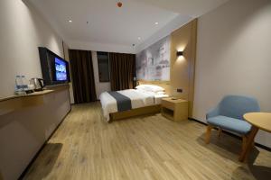 a hotel room with a bed and a chair at City Comfort Inn Zhongxiang Mochou Avenue in Zhongxiang