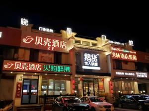 eine Gruppe von Gebäuden mit Neonschildern in der Nacht in der Unterkunft Shell Hotel Shanghai Jinshan Wanda Plaza in P'ai-ts'ang