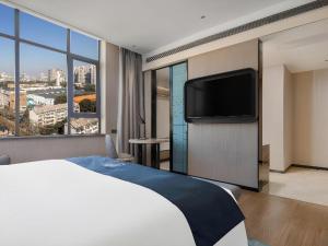 a hotel room with a bed and a flat screen tv at Echarm Hotel Changsha Wuyi Square Xiangya 2nd Hospital Metro Station in Changsha