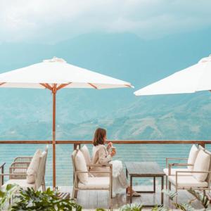 a woman sitting on a patio with a view of the ocean at Viettrekking Sapa in Lo Sui Tong