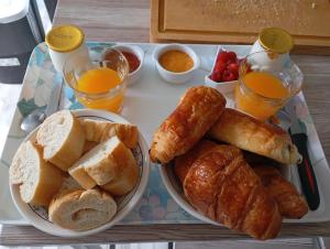 a tray with bread and croissants and glasses of orange juice at Écrin de tranquillité in Rosières-en-Santerre