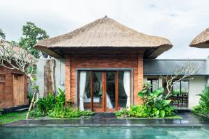 Villa con techo de paja y piscina en Novancha Villa, en Ubud