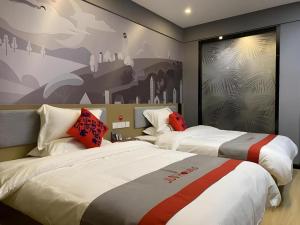 une chambre d'hôtel avec deux lits et un tableau au mur dans l'établissement Jun Hotel Jiangsu Nanjing Pukou District Linchang Metro Station, à Shenzhuang